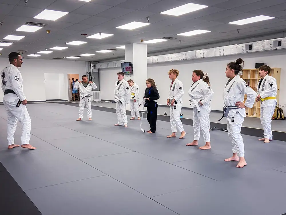A group of students standing attentive at class showing that kids jiu jitsu teaches discipline